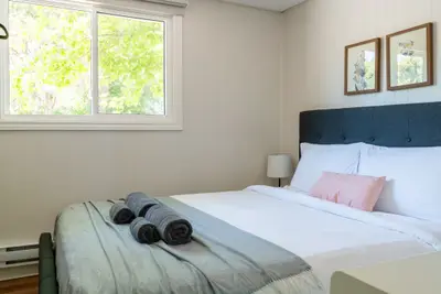 A bed with a navy headboard beside a bright window