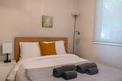 A bed with an ochre cushion and framed print above