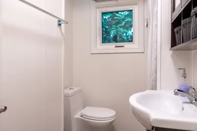 A bathroom with basin, toilet and a small high window