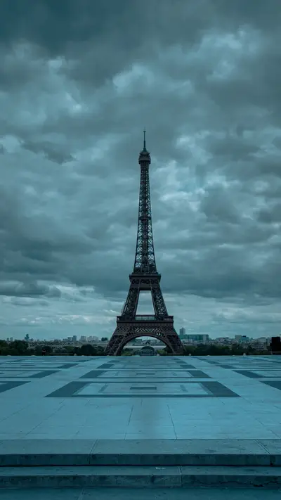 The Eiffel Tower under heavy cloud across the plaza