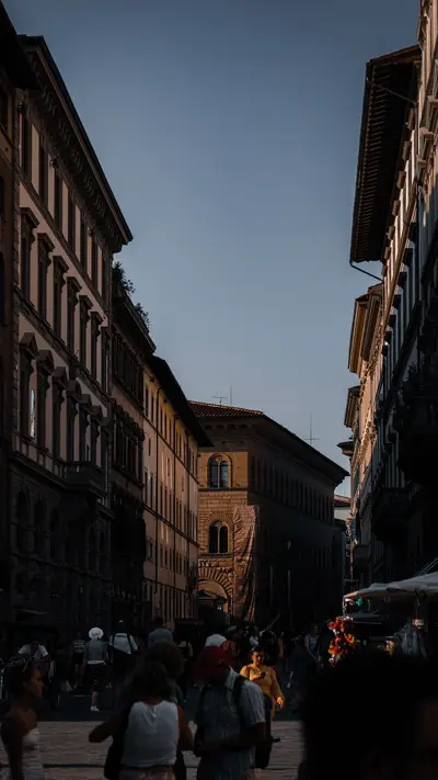 A narrow street busy with people between tall facades