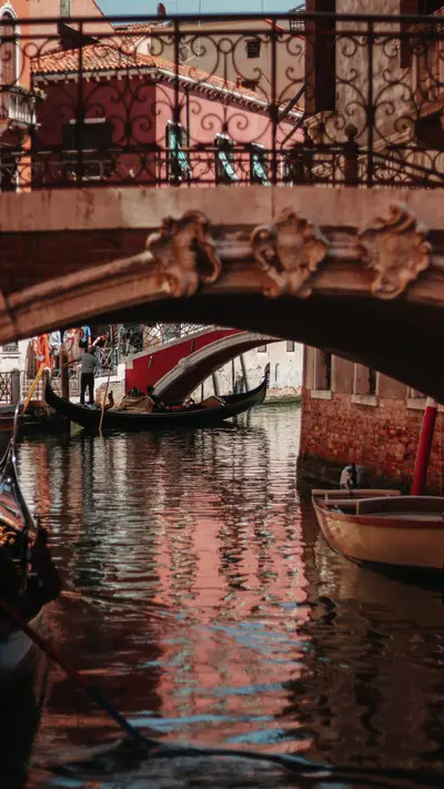 A stone bridge over a canal with a gondola beneath