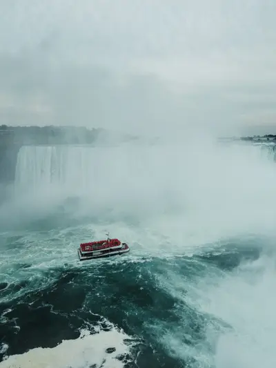 The falls in mist with a small boat below