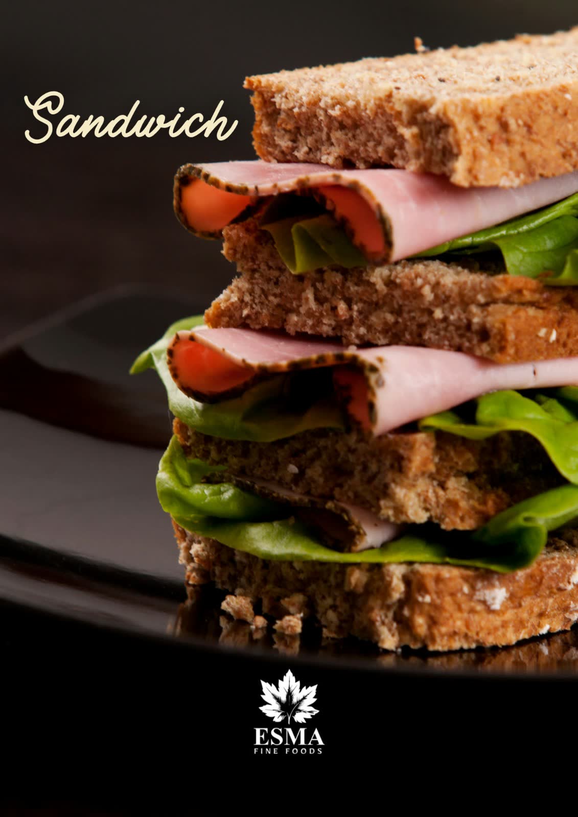 Stacked club sandwich with ham, tomato and lettuce on dark rye, photographed on a black plate